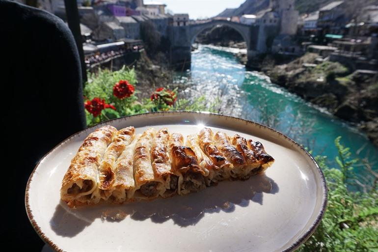 Burek probieren mit Blick auf die Brücke von Mostar, Bosnien